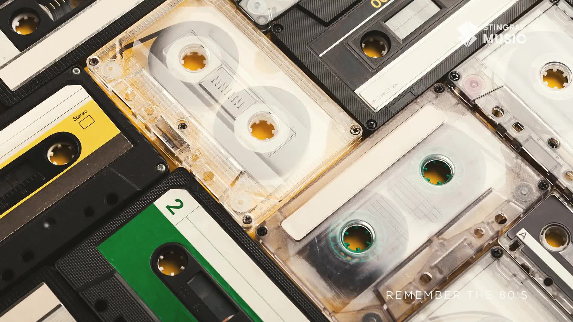 Cassette tapes in various colors and conditions are arranged together, their plastic cases reflecting the light. The Stingray Music logo and "Remember the 80's" text are visible, evoking a nostalgic feeling.
