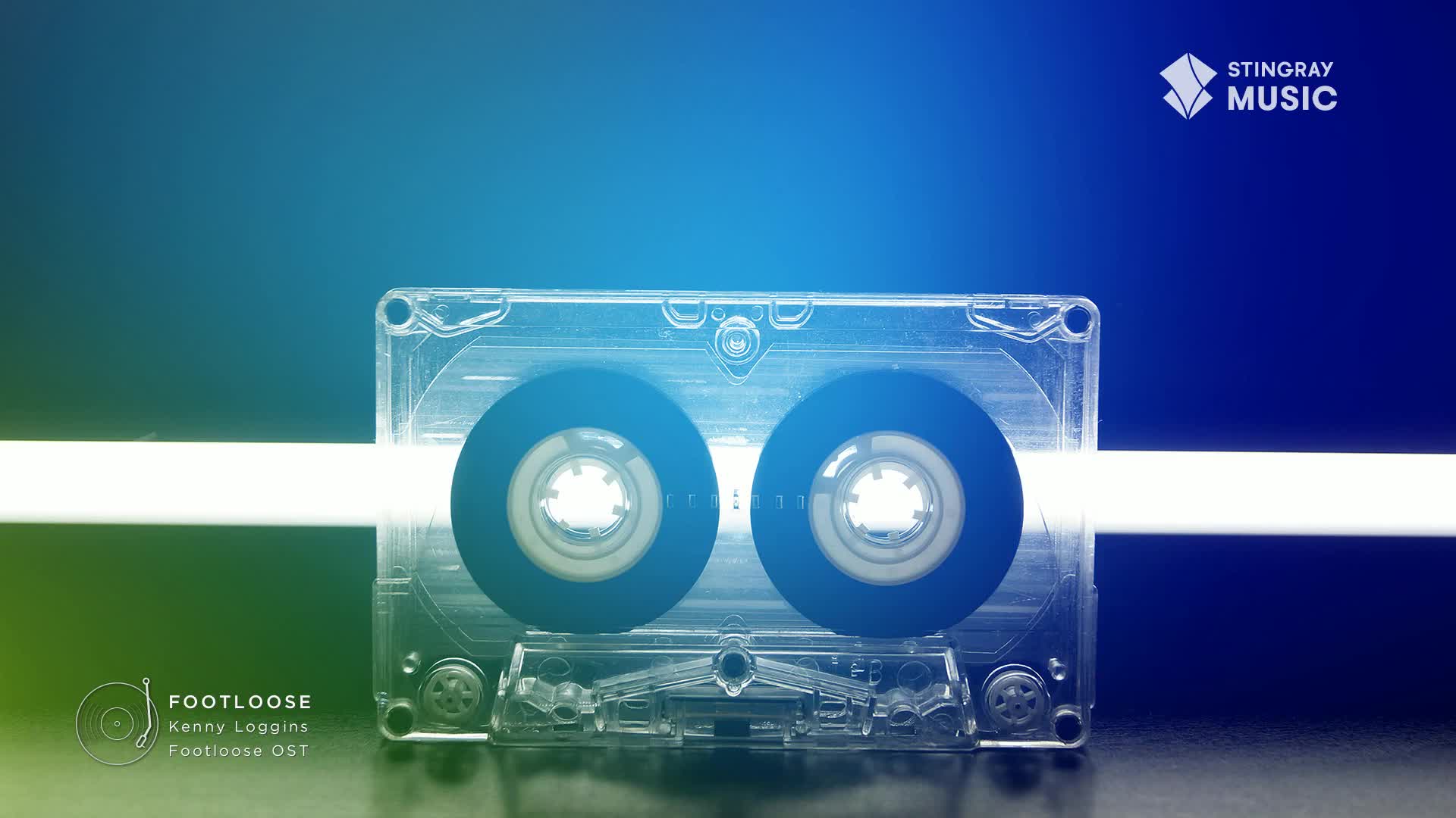 A clear cassette tape, lit by a horizontal white beam, sits against a gradient background. The "Footloose" album art, a Stingray Music logo, and a Canadian vibe are all present.
