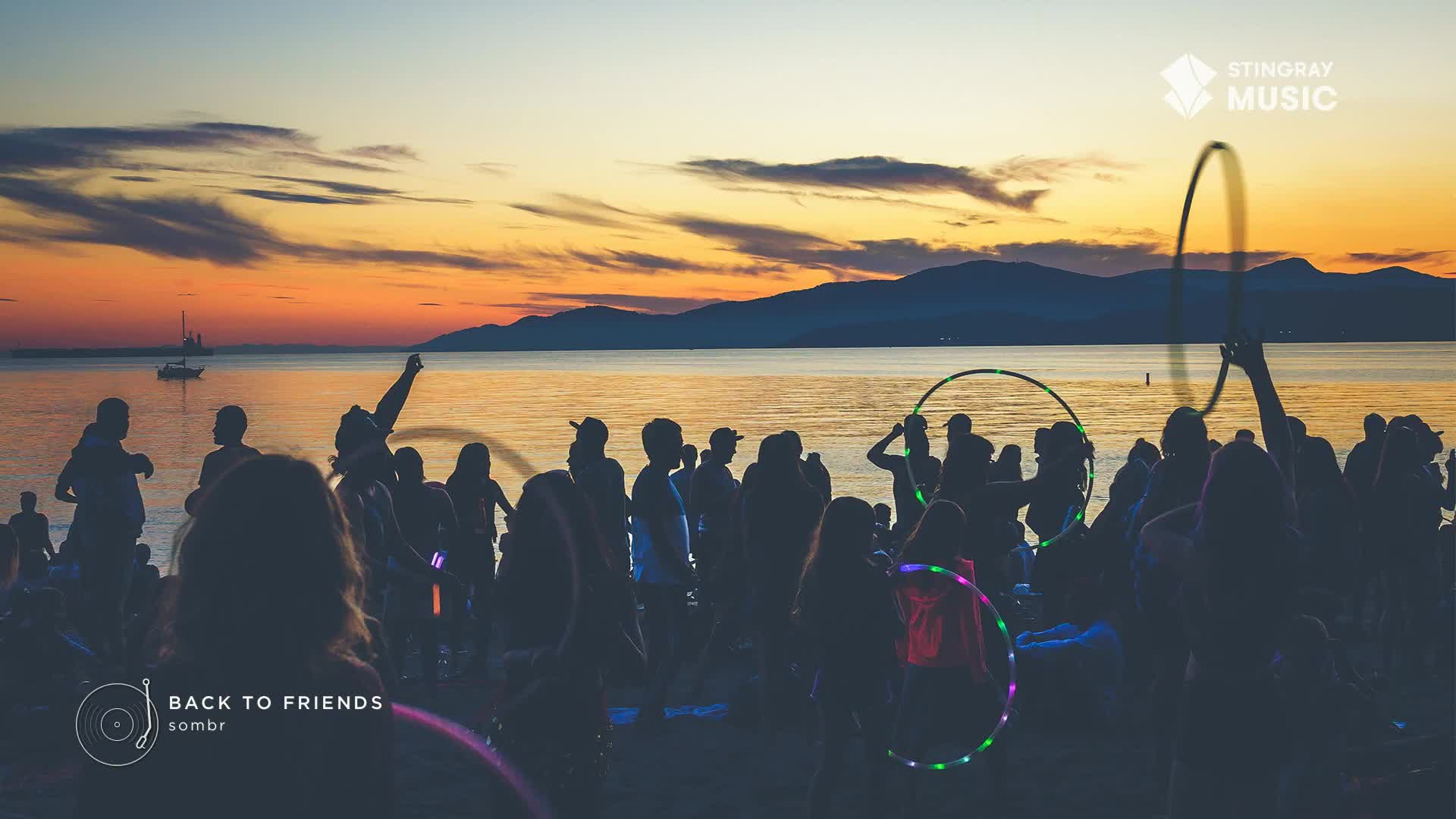 On a beach in Canada, a crowd dances to music, some twirling glowing hoops. The sunset casts long shadows over the water, and the Stingray Hit List is playing.
