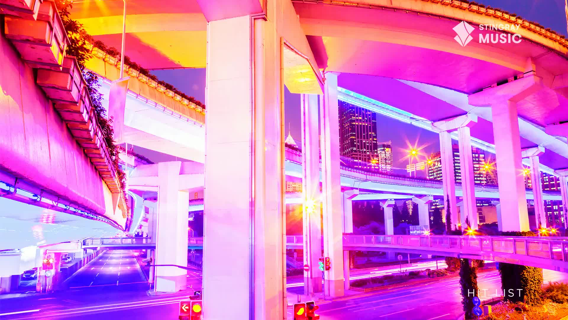 Underneath the elevated highway, the scene is awash in neon hues, with the Stingray Hit List logo visible. Cars are moving slowly on the road below, their taillights leaving streaks of red.
