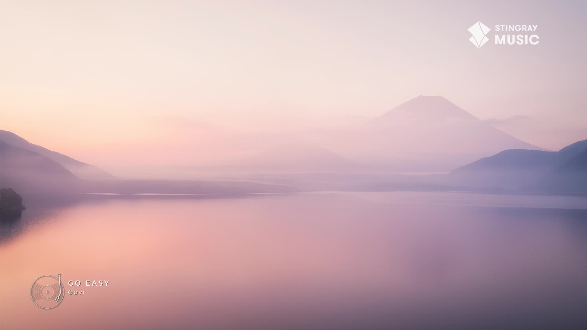 Mist hangs over the lake, softening the mountain peaks in the distance. The water reflects the pastel sky, a scene that feels like a Stingray The Spa ad in Canada.
