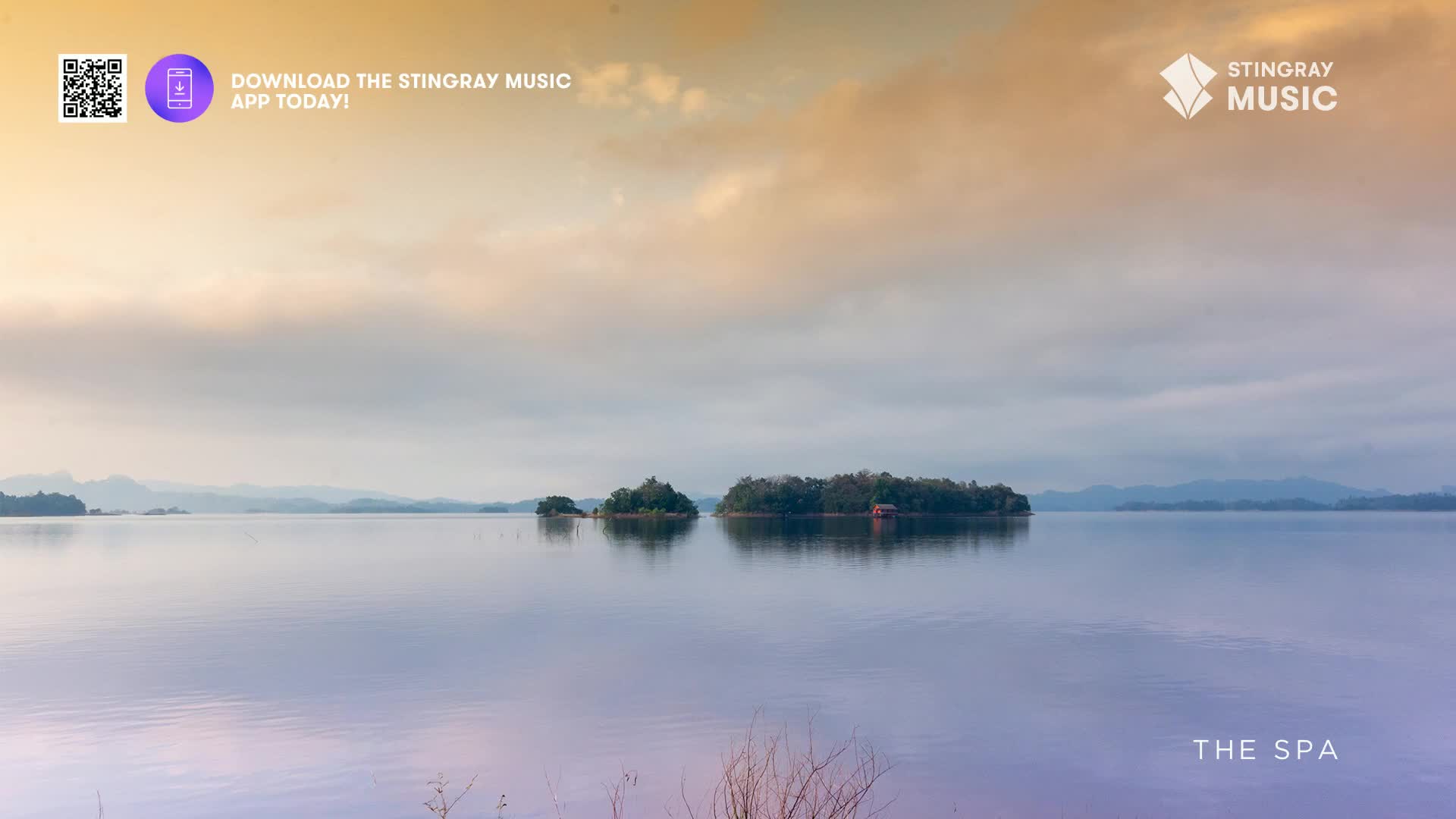The water is perfectly still, reflecting the soft, hazy sky. Islands dotted with trees rise from the calm surface, a small red building nestled on the largest one.