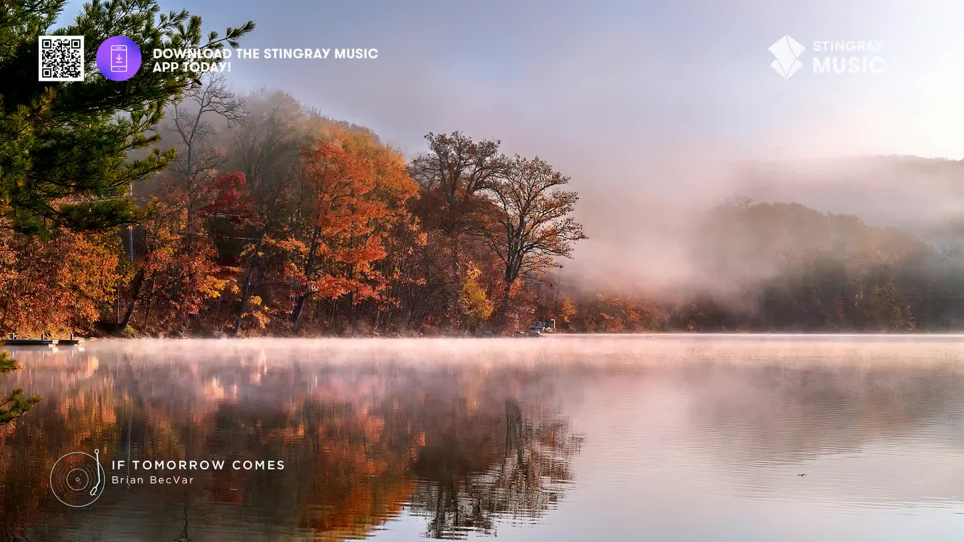 Mist rises off the still lake, reflecting the vibrant autumn trees lining the Canadian shore. A small boat rests near the bank, its silhouette softened by the morning fog.