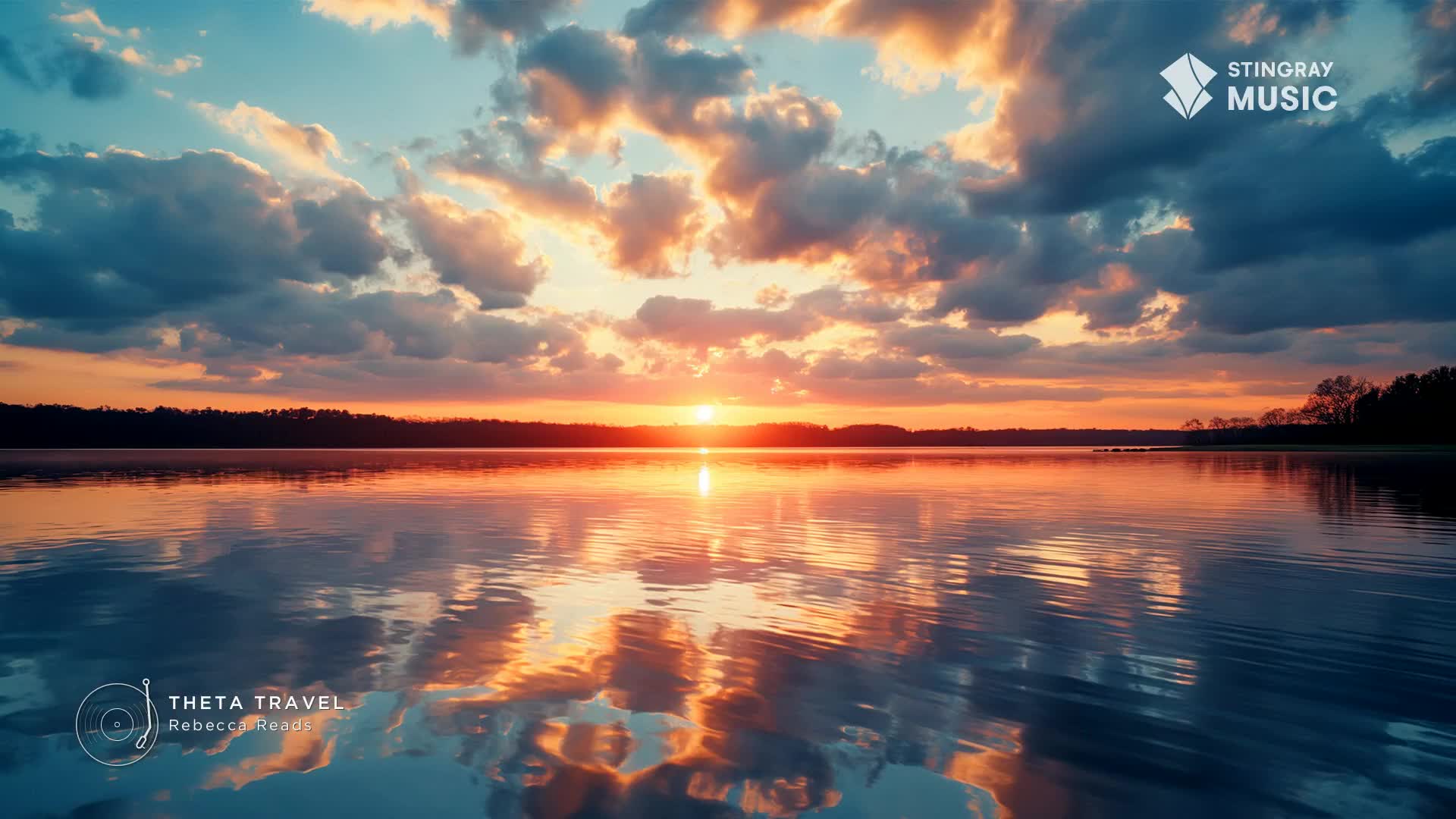 The sun dips below the tree line, painting the sky in fiery oranges and soft pinks. Its reflection shimmers across the calm water, mirroring the dramatic clouds above.