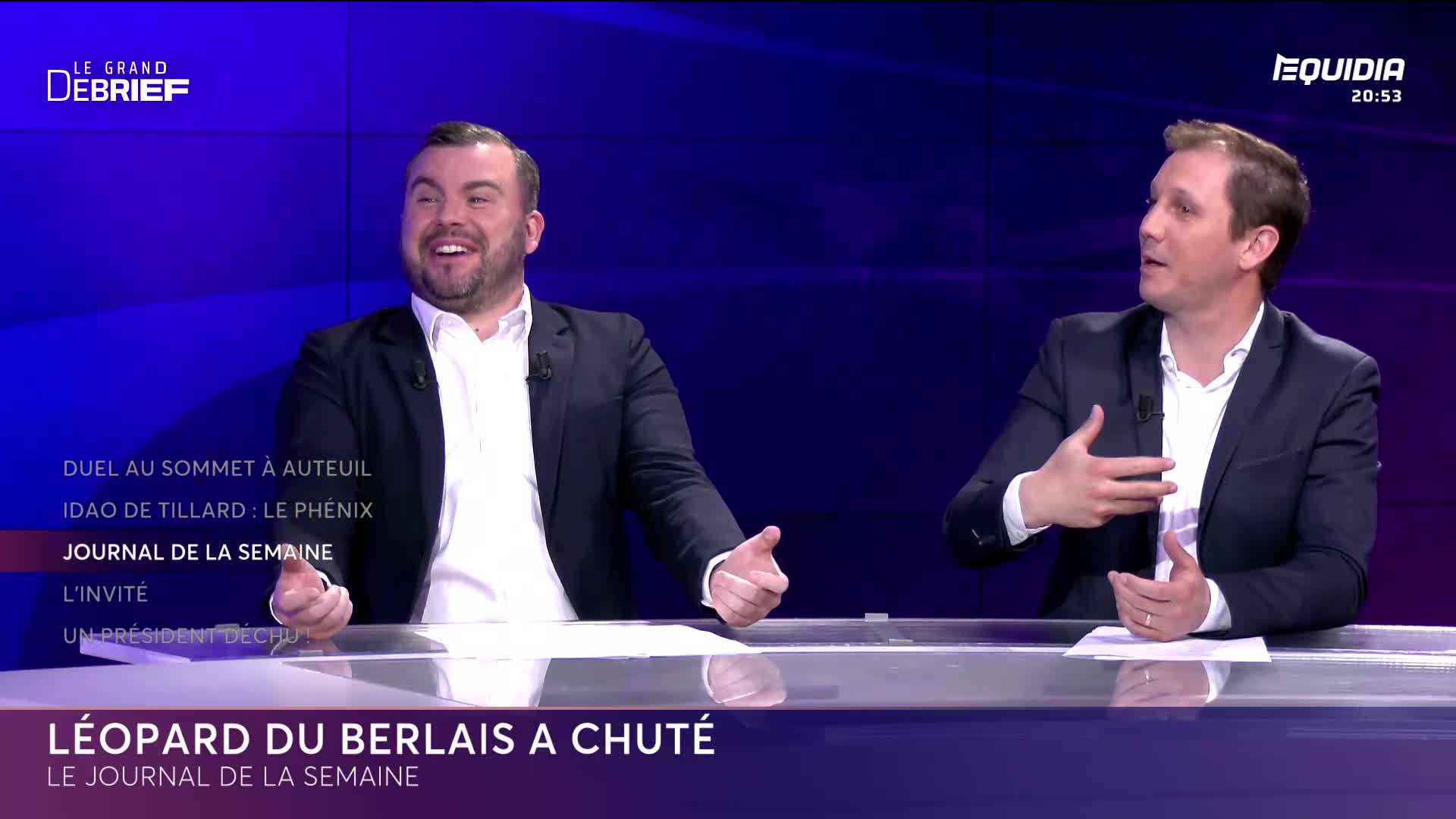 Two men in suits are seated at a desk, discussing something with animated gestures. The screen displays "LE GRAND DÉBRIEF" and "EQUIDIA" at the top.