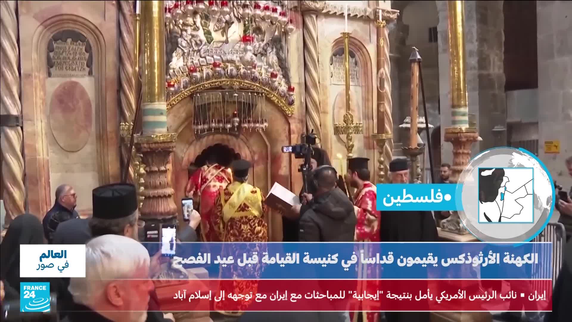 Clergy in ornate robes enter a small, ornate structure, holding books and candles. A camera operator films the procession as onlookers gather, some holding up their phones.