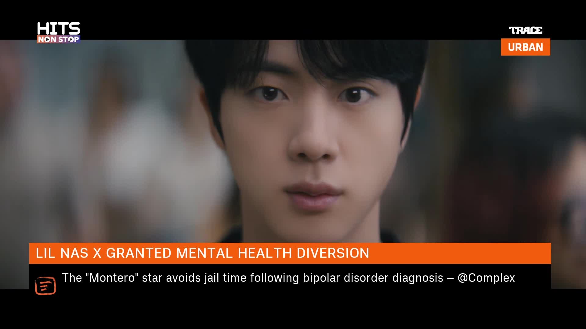 A young man with dark hair stares directly ahead, his expression unreadable. Below him, a news ticker announces Lil Nas X's mental health diversion, a detail that feels particularly relevant given the context of Trace Urban's programming.