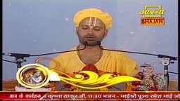 A man in a yellow turban and robe speaks into two microphones, his face illuminated. Behind him, a logo for "Aastha Bhajan" is visible.
