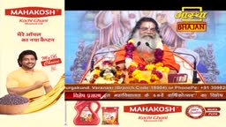 A man with a long white beard, wearing an orange robe and garlands, speaks into a microphone. Beside him, a screen displays "Aastha Bhajan" in bold yellow letters.