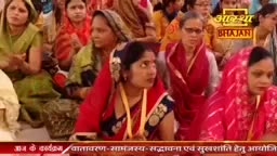 A group of women are seated, their faces turned slightly to the side. Their vibrant saris create a tapestry of color in the gathering.