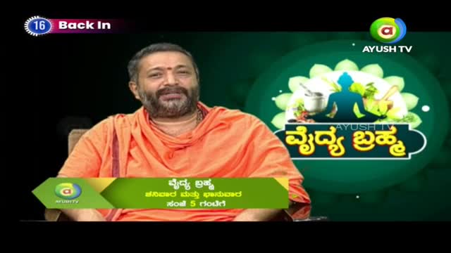 A man in an orange robe smiles at the camera. A graphic behind him displays the Ayush TV logo and Kannada text.