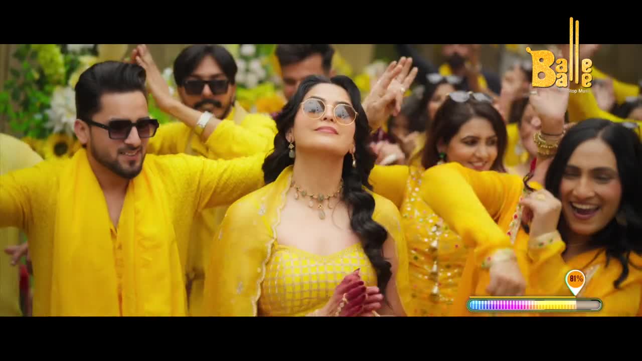 A group of people in vibrant yellow clothing are dancing joyfully. Their hands are raised and their faces are alight with laughter.