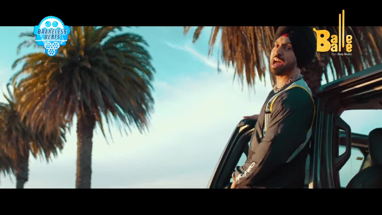 A man in a black turban leans out of a car door, his mouth open as if singing. Tall palm trees sway against a bright sky, hinting at a warm, sunny day.