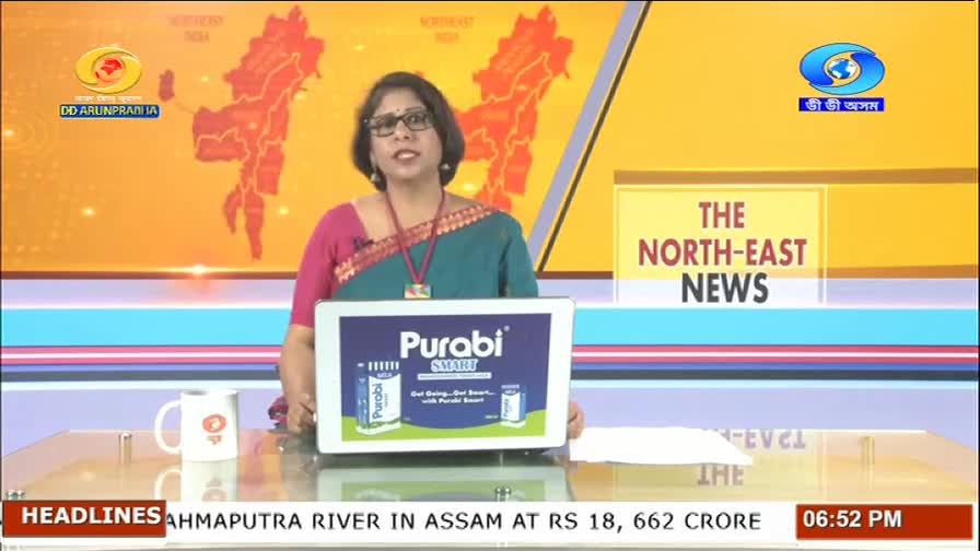 A woman in a teal and pink sari stands behind a desk, presenting information on a tablet. The DD Arun Prabha logo is visible on the screen behind her, alongside the words "THE NORTH-EAST NEWS."