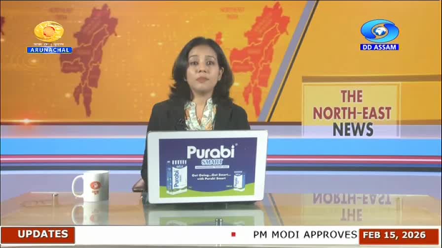 A woman in a dark blazer is presenting news for DD Assam. A tablet in front of her displays an advertisement for "Purabi Smart." A woman in a dark blazer is presenting news for DD Assam. A tablet in front of her displays an advertisement for "Purabi Smart."