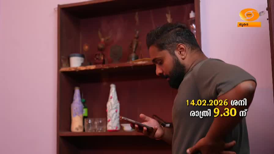 A man is looking at his phone, his thumb scrolling down the screen. Behind him, a wooden shelf holds decorative bottles and small statues. A man is looking at his phone, his thumb scrolling down the screen. Behind him, a wooden shelf holds decorative bottles and small statues.