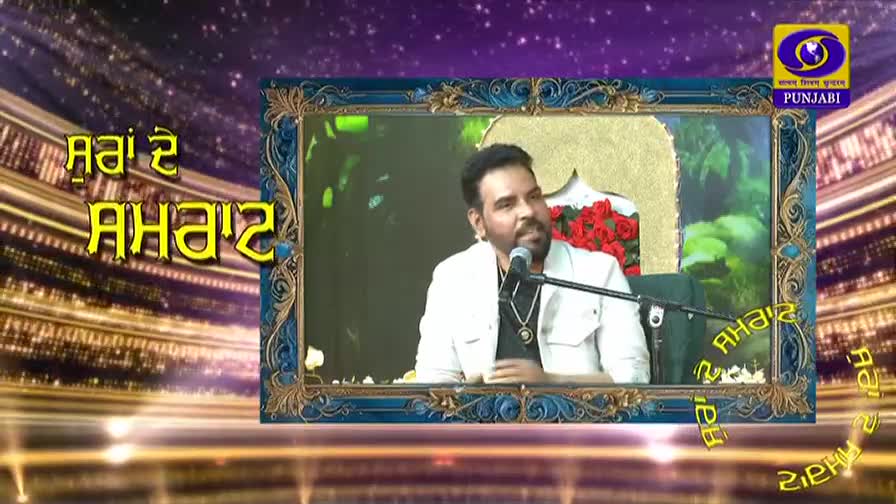 A man in a white jacket speaks into a microphone, framed by a decorative border. The DD Punjabi logo sits in the corner of the screen. A man in a white jacket speaks into a microphone, framed by a decorative border. The DD Punjabi logo sits in the corner of the screen.