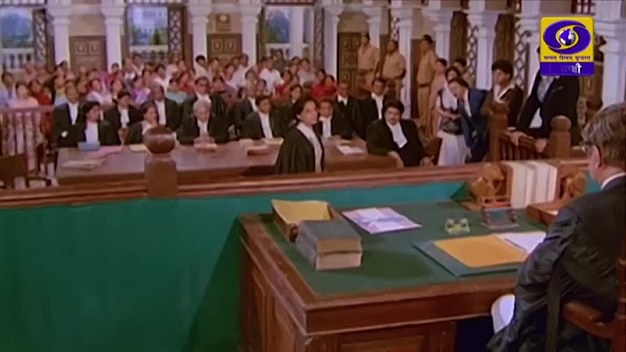 A woman in a dark robe stands, facing the crowd filling the benches.  The DD Punjabi logo is visible in the corner.