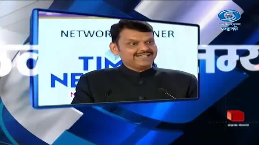 A man in a black jacket speaks into a microphone, his face lit by the screen behind him. The DD Sahyadri logo is visible in the corner.