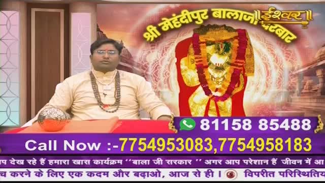 A man in a cream-colored kurta sits at a table, a beaded necklace around his neck. Behind him, a vibrant image of a deity is displayed, with text in Hindi and phone numbers for "Ishwar Darbar" and "Bala Ji Sarkar" programs on Ishwar Bhakti TV.