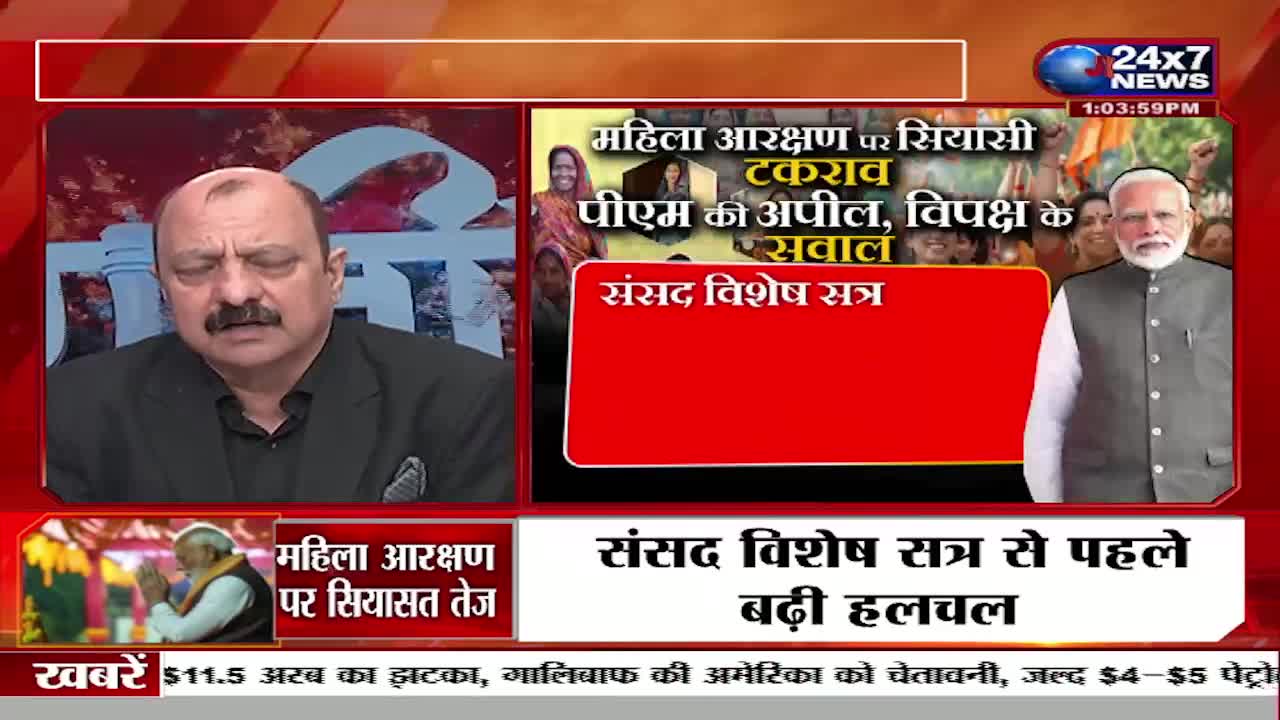 A man with a mustache, wearing a black suit, speaks with his eyes closed. To his right, Prime Minister Modi stands smiling, surrounded by a crowd.