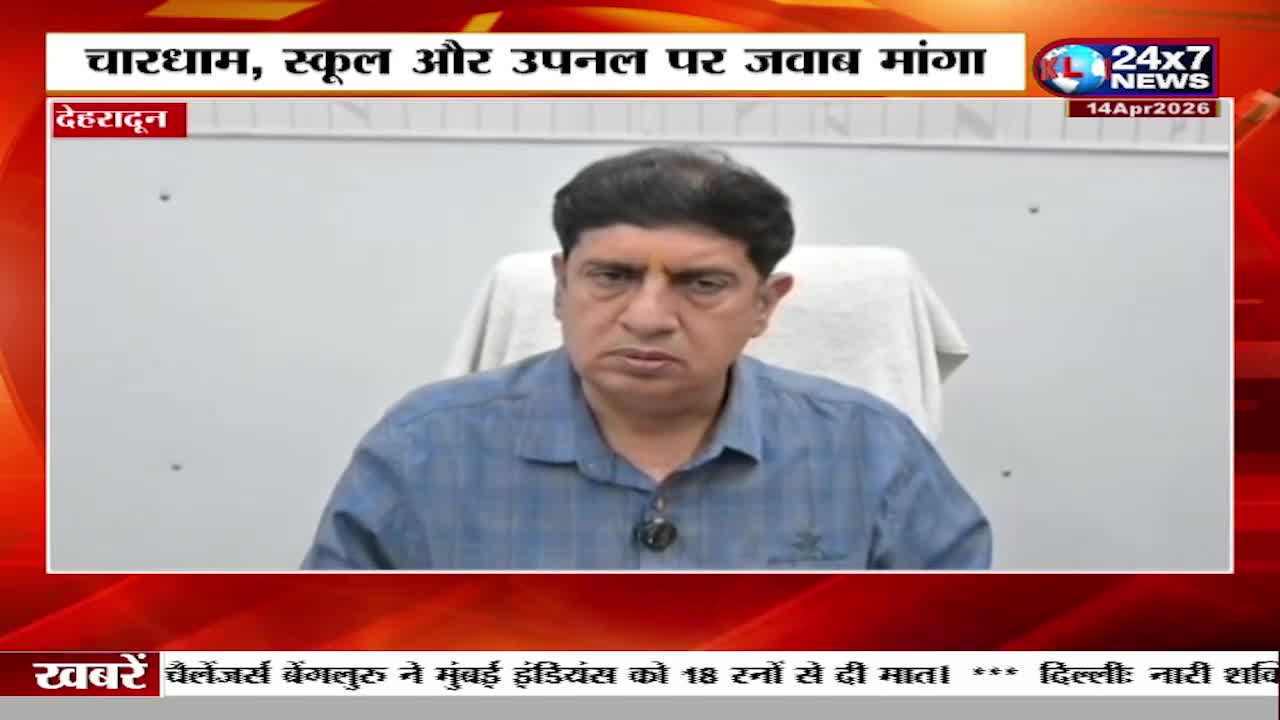 A man in a blue shirt sits in front of a white wall, looking directly ahead. A news ticker scrolls across the bottom of the screen, reporting on events in India.