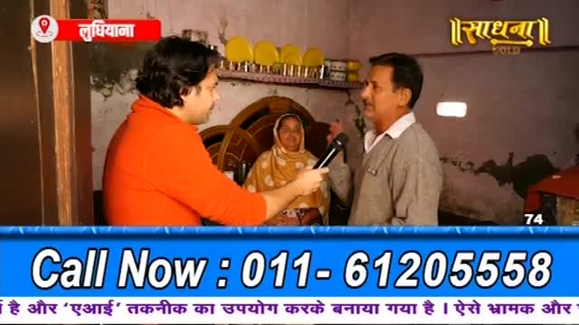 A man in an orange shirt interviews a man in a grey sweater, while a woman in a headscarf sits behind them. The interview is taking place in what appears to be a home in Ludhiana, India.