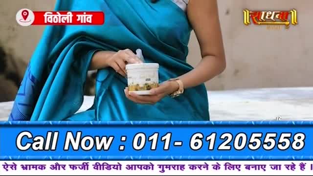 A woman in a bright blue sari holds a small white container. The text at the bottom of the screen displays a phone number and a warning in Hindi.