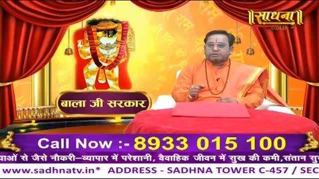 A man in an orange robe speaks with his hand raised, gesturing towards a large image of a deity. A phone number flashes across the bottom of the screen, inviting viewers to call.