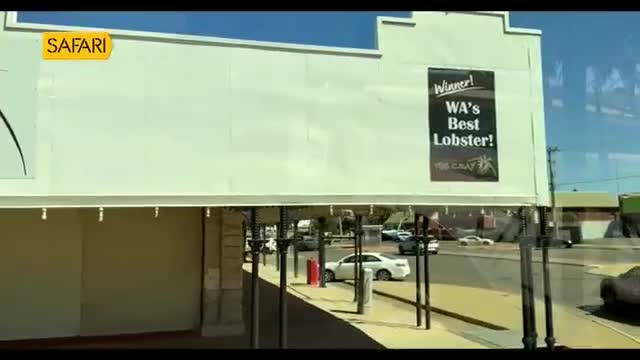 A white sedan turns onto the street, passing a bright red bin. A black banner on the building declares "WA's Best Lobster!"