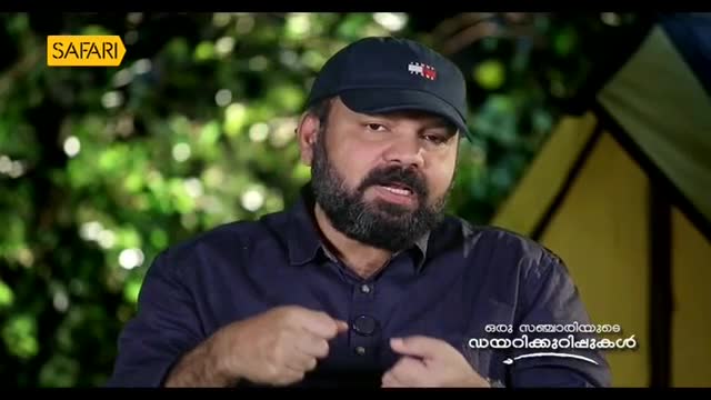 A man with a beard and a cap is speaking, his hands gesturing. The Safari TV logo is visible in the upper left corner.