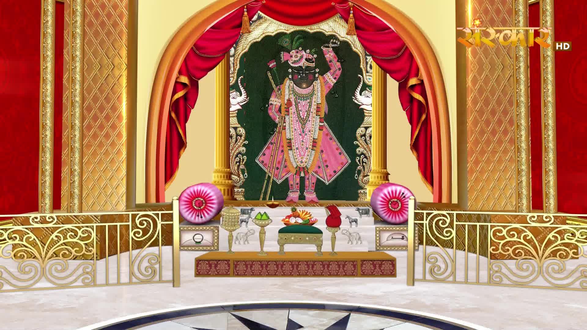 A divine image of Lord Krishna stands on a raised platform, adorned in vibrant pink and gold. The scene is framed by rich red drapery and ornate golden pillars, a familiar sight on Sanskar TV.