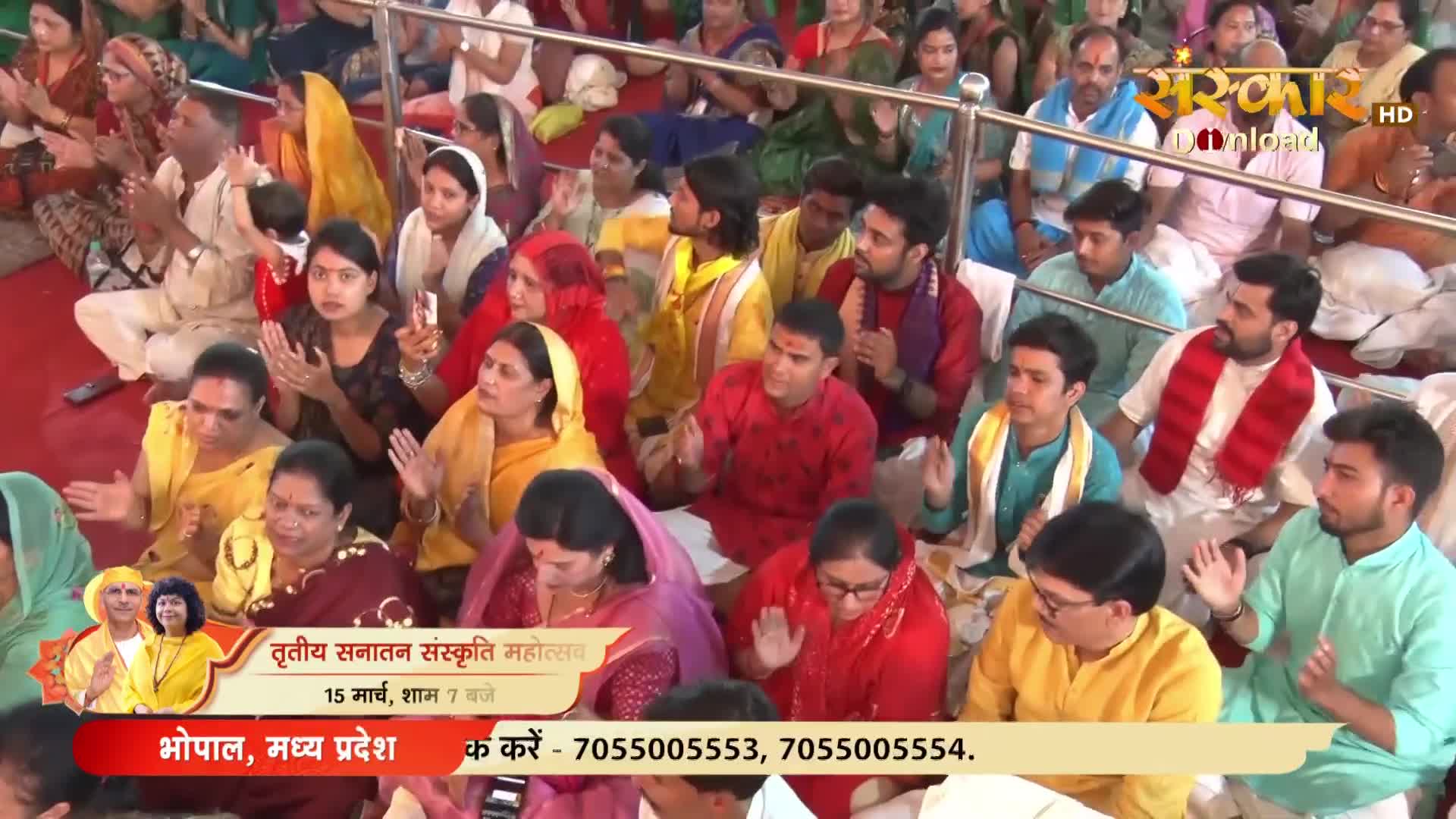 The crowd claps along to the music, their hands raised in unison. A banner for Sanskar TV announces the "Tritiya Sanatan Sanskriti Mahotsav" in Bhopal.