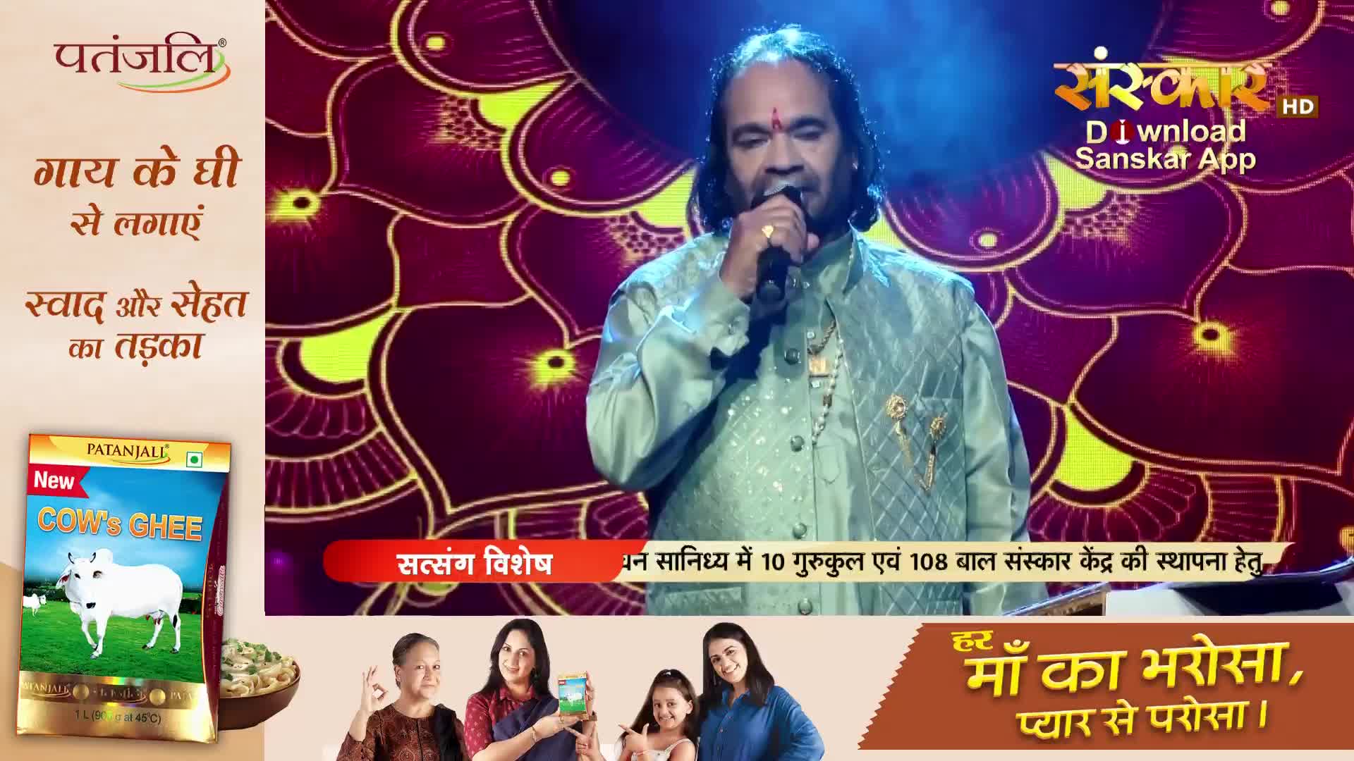 A man in a light green kurta sings into a microphone on a stage. The Sanskar TV logo is visible above him.