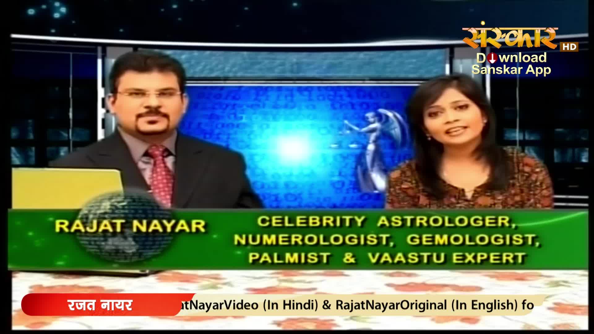 A man with glasses and a red tie sits to the left, while a woman with a patterned blouse speaks on the right. Their names appear on screen, identifying them as experts in astrology and related fields.