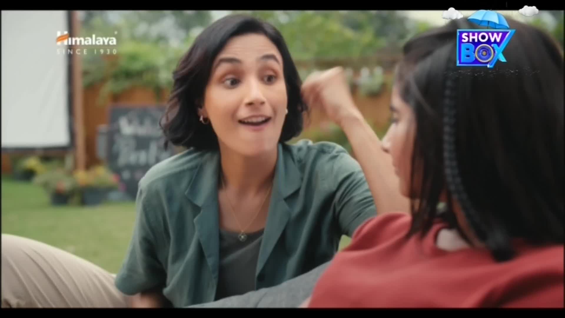 A woman in a green shirt gestures animatedly, speaking with wide eyes to someone out of frame. The ShowBox logo sits in the corner, and the Himalaya logo is visible in the background.
