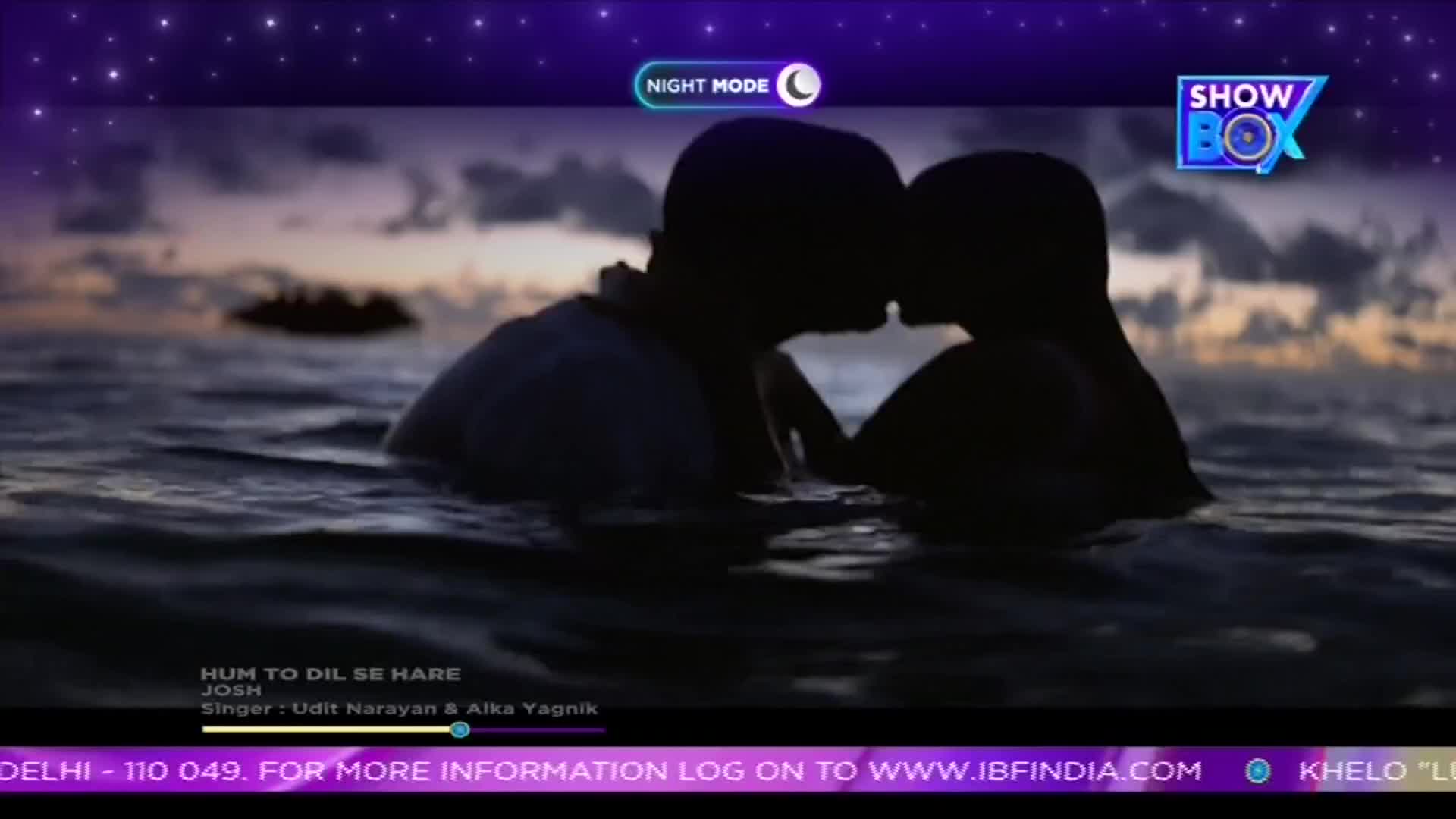 Two figures embrace in the water, their faces close as they kiss. The scene plays on ShowBox, with a song from India playing in the background.
