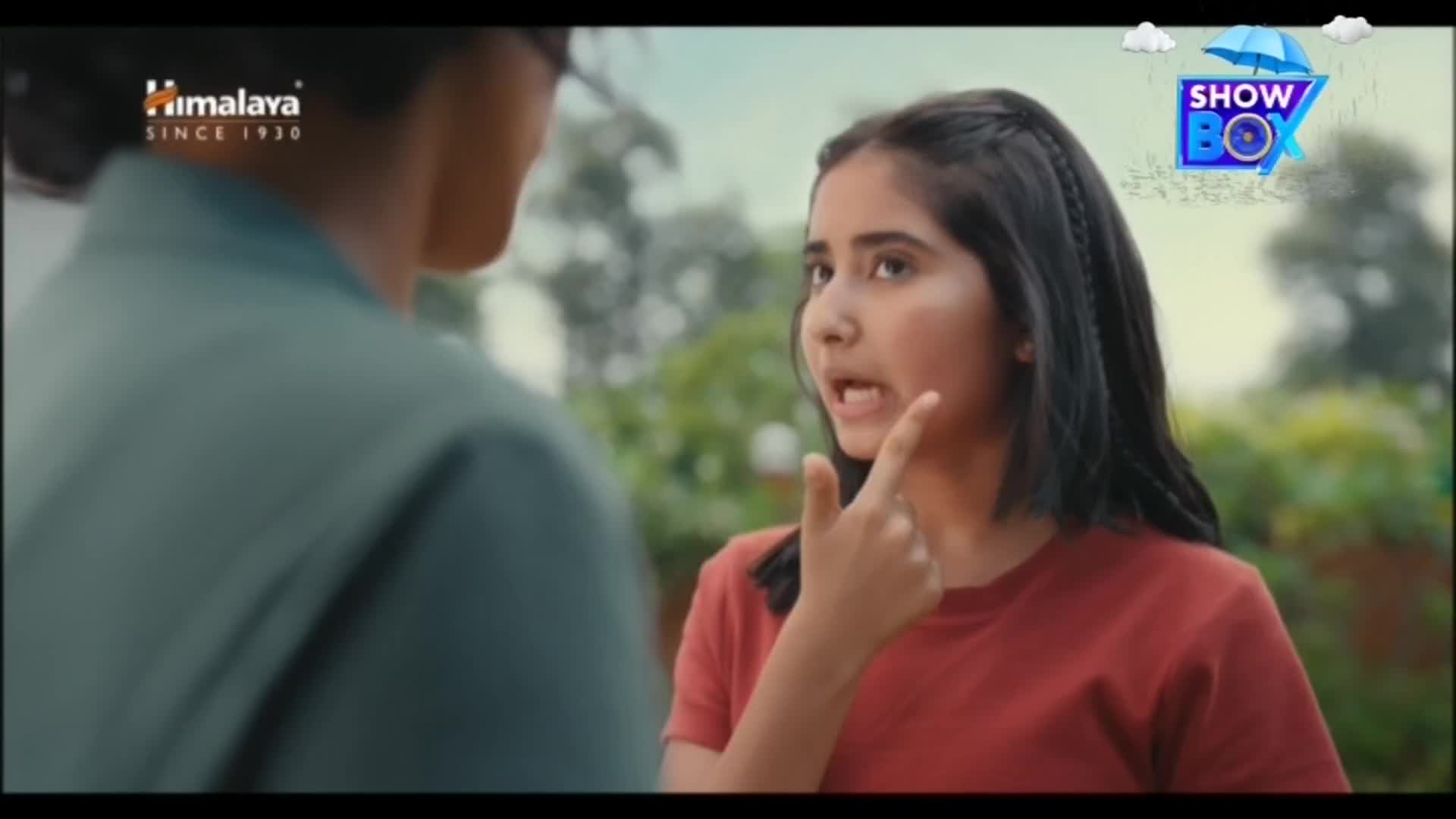 A girl in a red shirt gestures emphatically, her finger pointing as she speaks to someone out of frame. The ShowBox logo sits in the corner, and a Himalaya ad is visible.
