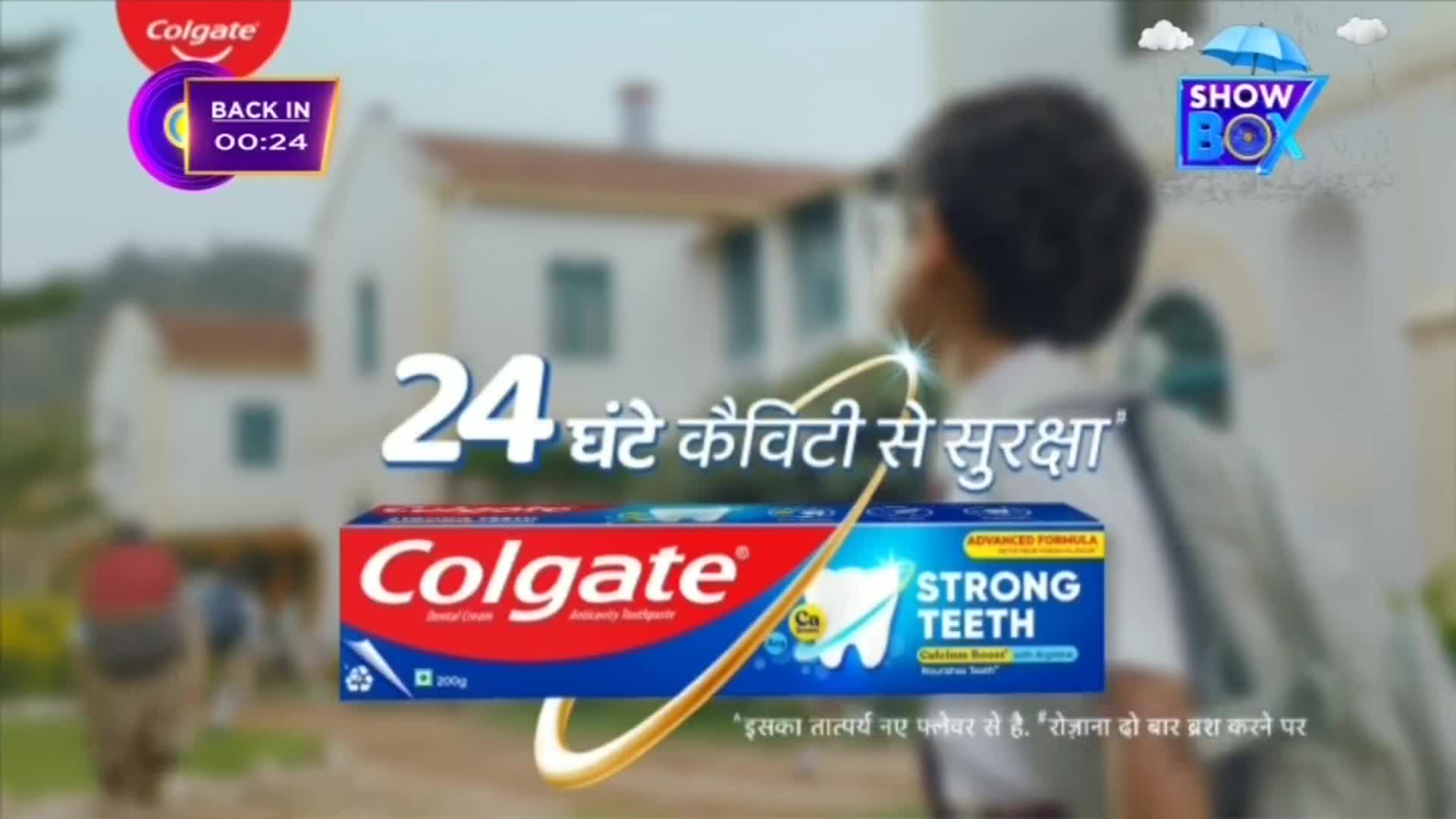 A toothpaste ad is playing on ShowBox, with a school-aged child walking in the background. The Colgate box, with Hindi text, is the focus, along with the promise of 24-hour cavity protection.
