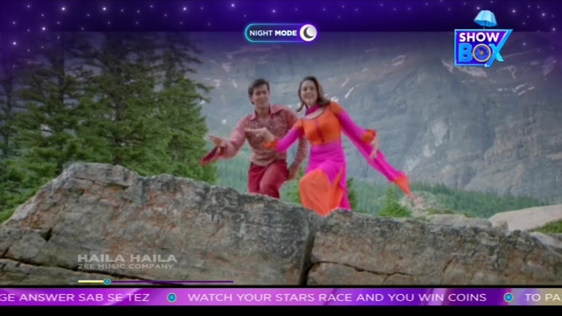 A man and a woman in bright, flowing clothes are dancing on a rocky outcrop, arms outstretched. The scene is framed by a ShowBox logo and a starry night sky overlay.

