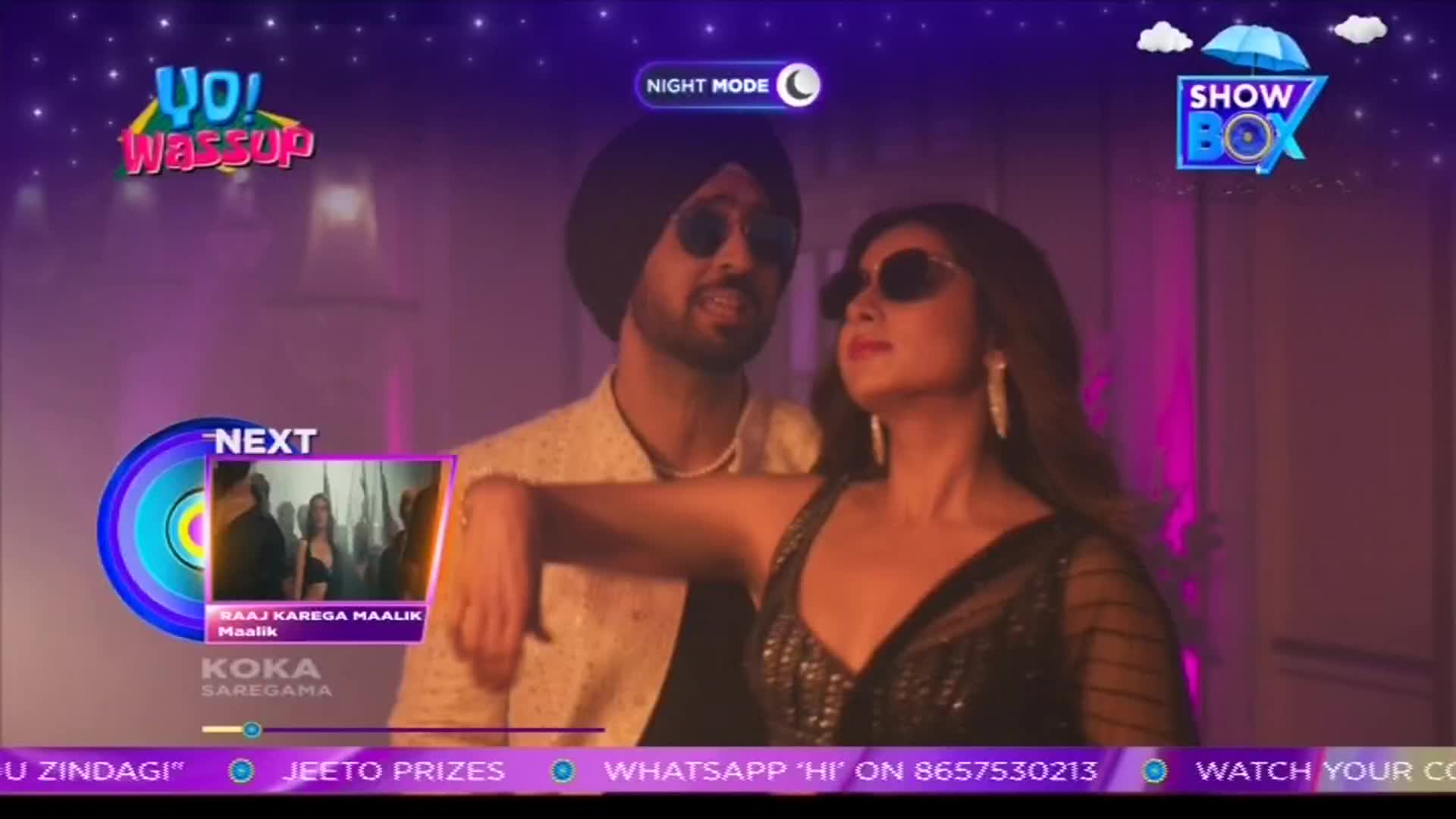 A man and woman in sunglasses are posing, the woman's arm resting on his shoulder. The ShowBox logo and a "Night Mode" indicator are visible, hinting at a music video on an Indian television channel.
