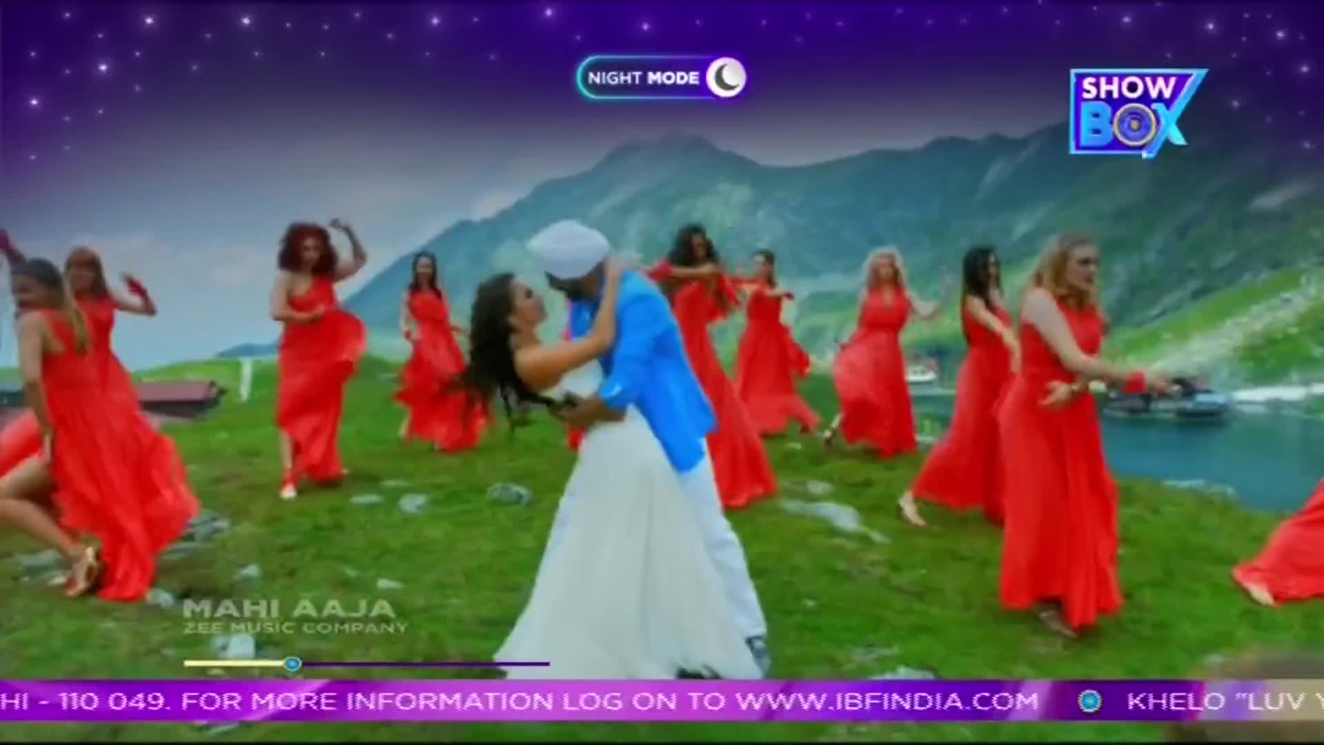 A man in a blue jacket and white turban embraces a woman in a white gown as a group of women in vibrant red dresses dance around them. The ShowBox logo hovers above the mountainous landscape, hinting at an Indian music video. A man in a blue jacket and white turban embraces a woman in a white gown as a group of women in vibrant red dresses dance around them. The ShowBox logo hovers above the mountainous landscape, hinting at an Indian music video.