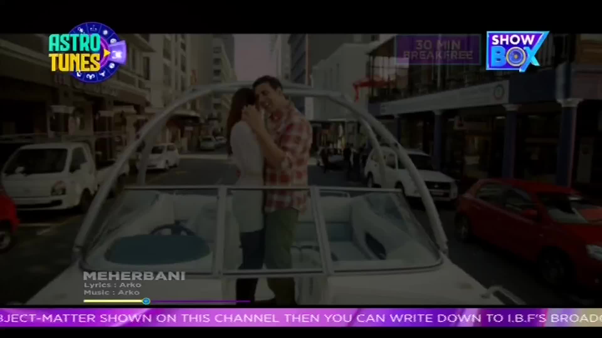 A couple embraces on a boat cruising down a city street, cars passing by on either side. The "MEHERBANI" song plays on ShowBox, with lyrics and music credits displayed at the bottom. A couple embraces on a boat cruising down a city street, cars passing by on either side. The "MEHERBANI" song plays on ShowBox, with lyrics and music credits displayed at the bottom.