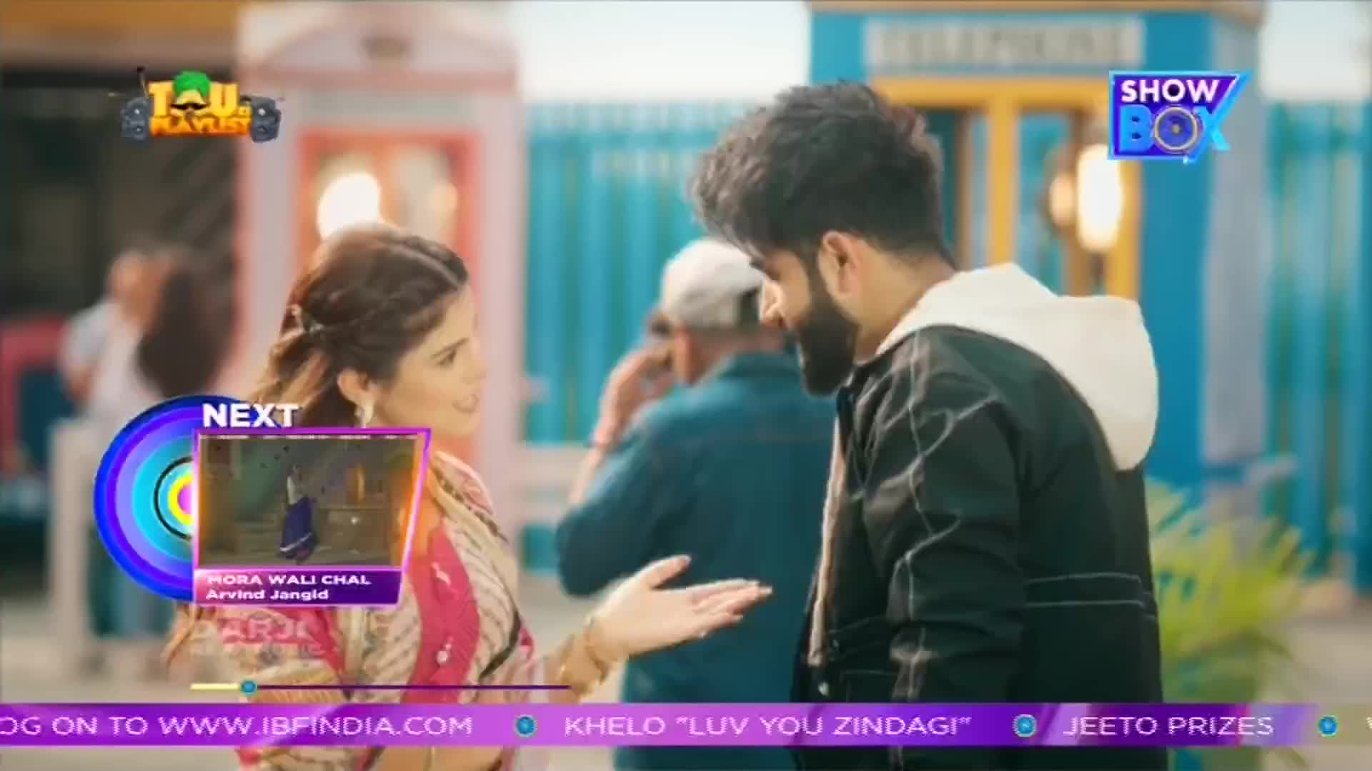 A young couple stands close, the woman in a bright pink and white salwar kameez, the man in a black jacket. A preview for the next song, "Hona Wali Chal" by Arvind Jangid, plays on the left. A young couple stands close, the woman in a bright pink and white salwar kameez, the man in a black jacket. A preview for the next song, "Hona Wali Chal" by Arvind Jangid, plays on the left.