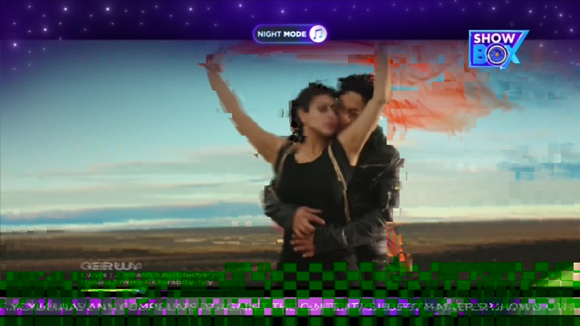 A couple embraces, a vibrant red fabric swirling around them against a vast, pale sky. The ShowBox logo is visible in the upper right corner. A couple embraces, a vibrant red fabric swirling around them against a vast, pale sky. The ShowBox logo is visible in the upper right corner.