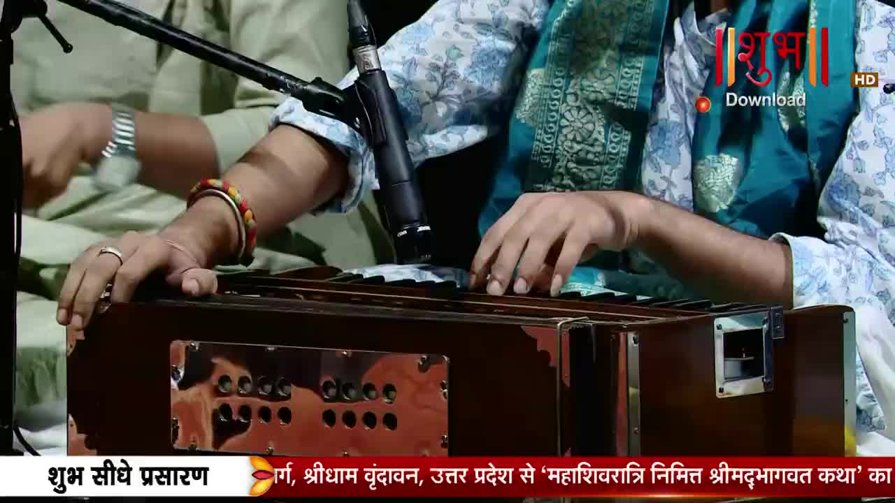 Fingers dance across the harmonium keys, their rhythmic press echoing the devotional music. A vibrant bracelet adorns one wrist, a splash of color against the instrument's polished wood.