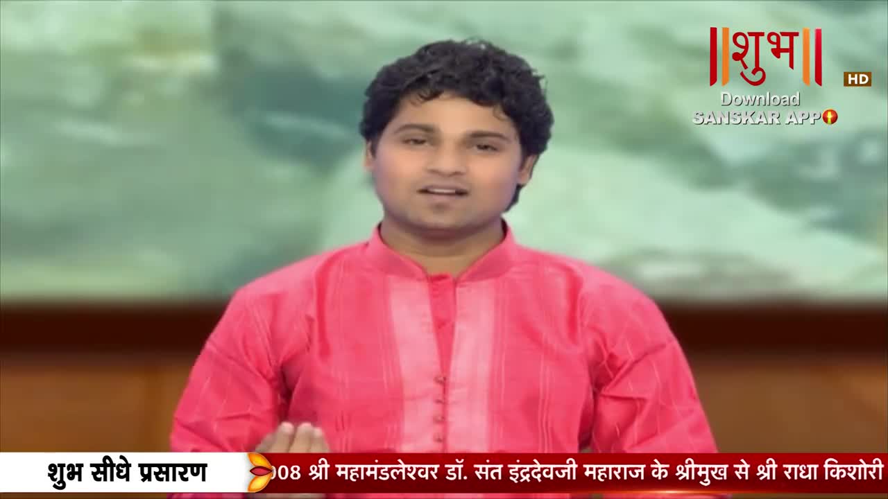 A young man in a bright pink kurta speaks directly to the camera. Text at the bottom of the screen indicates this is a live broadcast from India, featuring Shri Mahamandleshwar Dr. Sant Indradevji Maharaj.