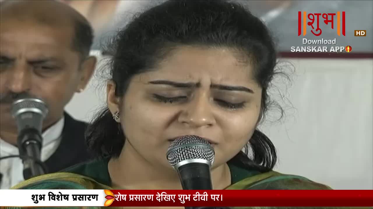 A young woman sings into a microphone, her eyes closed with emotion. Behind her, a man with a mustache also leans towards a mic. The Shubh TV logo is visible in the upper right corner.