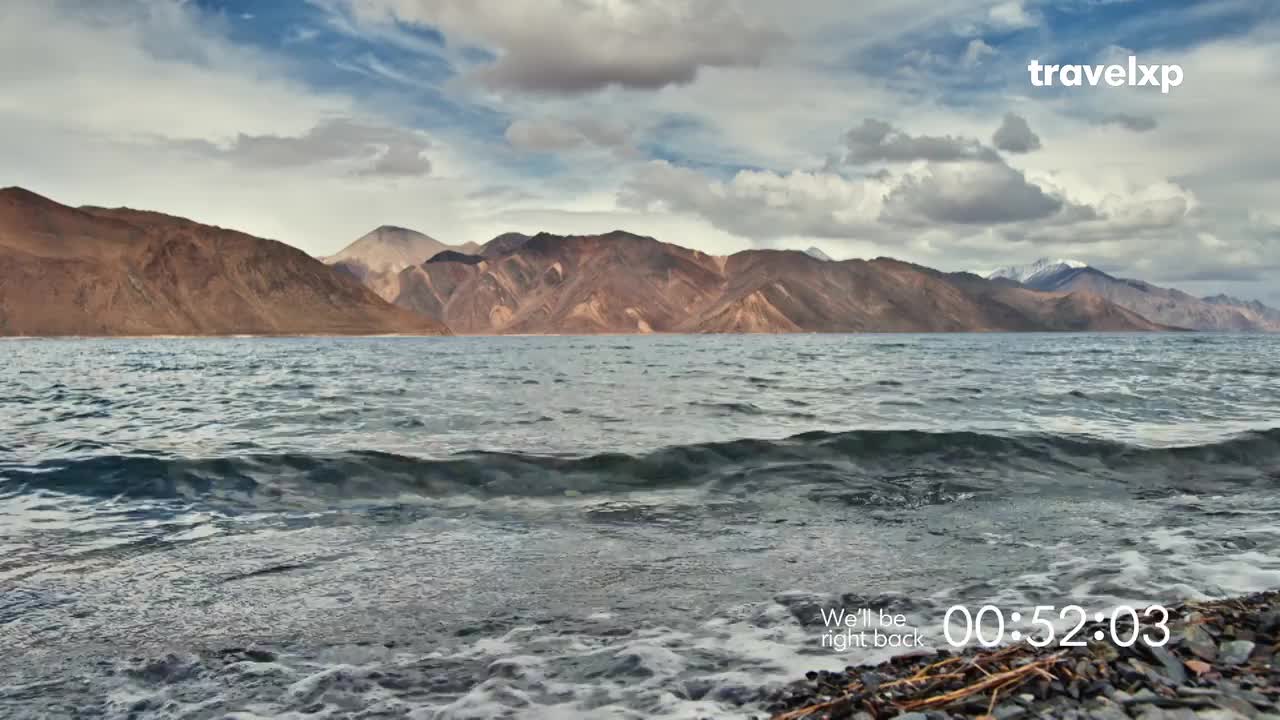 The waves gently lap the rocky shore, while the majestic mountains of India rise in the distance. The Travelxp logo and a countdown timer signal a break in the program.
The waves gently lap the rocky shore, while the majestic mountains of India rise in the distance. The Travelxp logo and a countdown timer signal a break in the program.