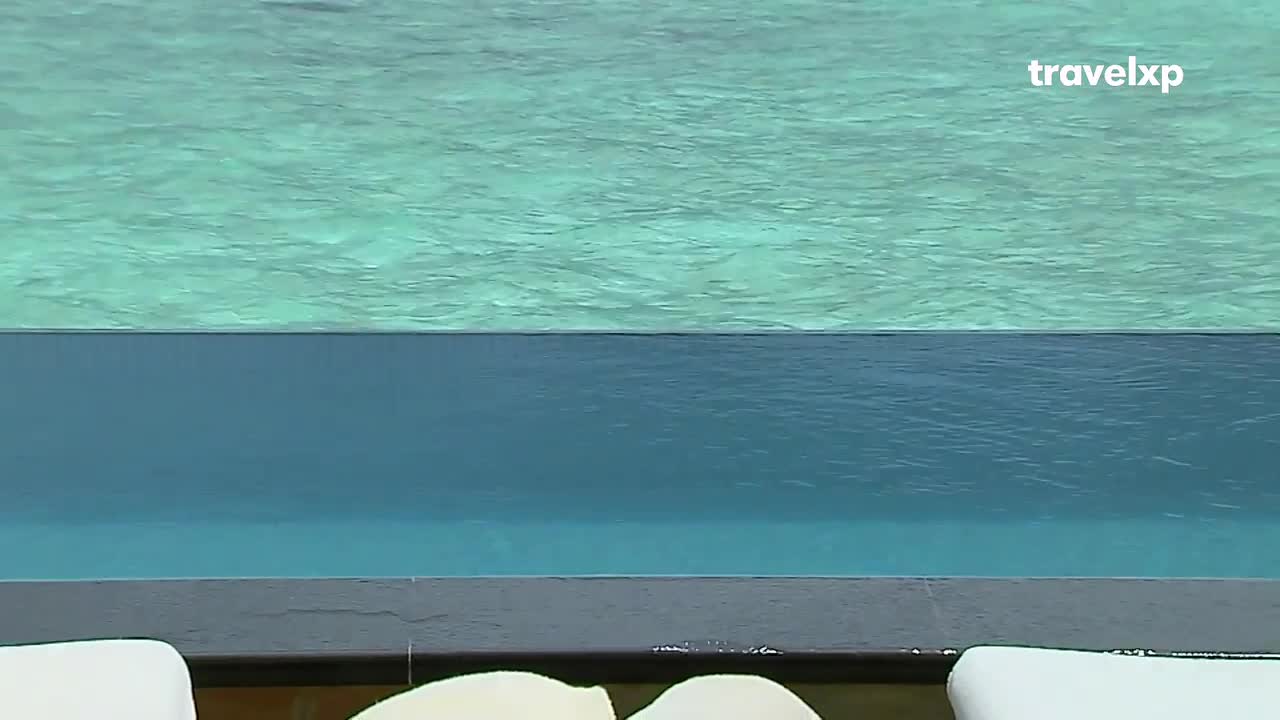 The turquoise water of the infinity pool stretches out before me, meeting the deeper blue of the pool itself. This tranquil scene, a perfect escape for any traveler, is brought to you by Travelxp. The turquoise water of the infinity pool stretches out before me, meeting the deeper blue of the pool itself. This tranquil scene, a perfect escape for any traveler, is brought to you by Travelxp.